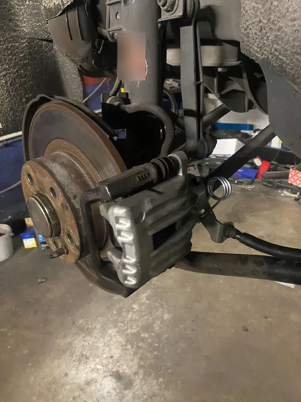 Disco y pinza de freno de un coche en el elevador, con la rueda quitada.