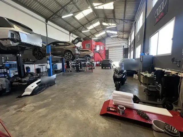 La nave del taller con coches en los elevadores